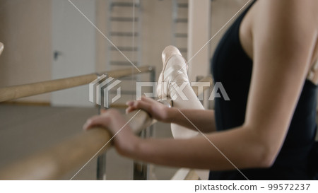 Female ballet dancer stands near ballet barre Female ballet dancer stands near ballet barre 99572237