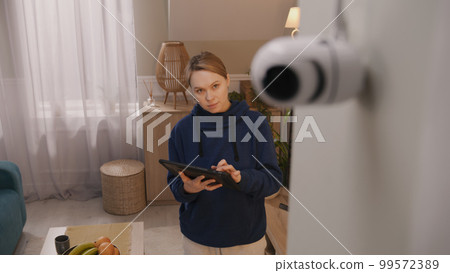 Woman installs CCTV camera using tablet Woman installs CCTV camera using tablet 99572389