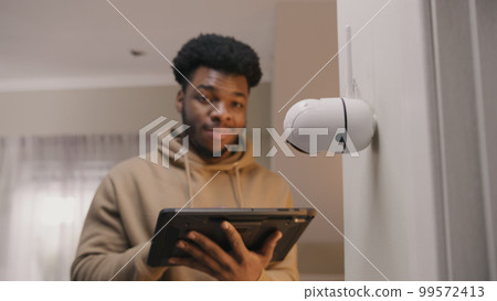 Man sets up security camera with tablet Man sets up security camera with tablet 99572413