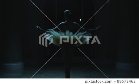 Ballerina rehearses in dark theater lobby at night 99572462
