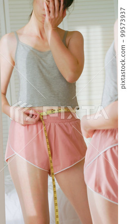 unhappy woman measure her waist unhappy woman measure her waist 99573937