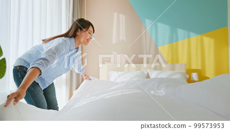 woman changes bed quilt 99573953
