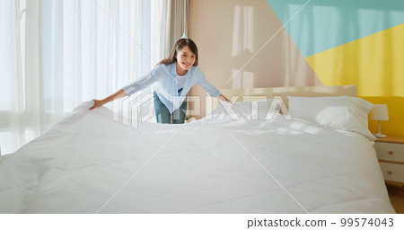 woman changes bed quilt 99574043