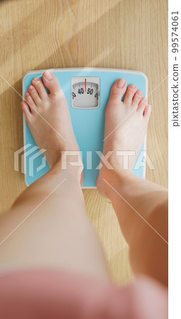 woman measure weight on scale 99574061