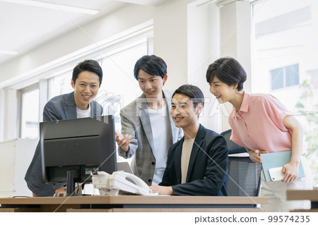 Four office workers looking at a desktop computer display Four office workers looking at a desktop computer display 99574235