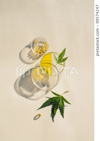 Cannabis leaves, CBD oil and capsules in transparent labware 99574247