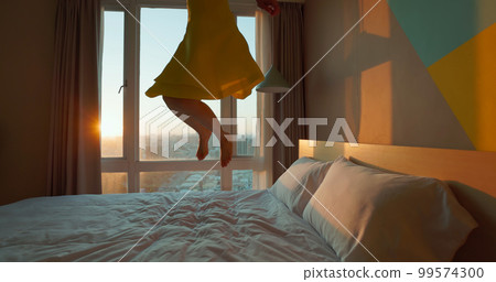 happy woman jump on bed 99574300
