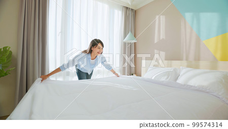 woman changes bed quilt 99574314