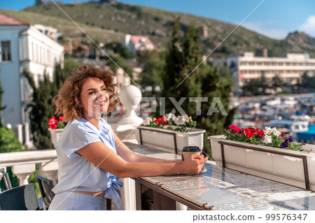 Happy beautiful woman drinking coffee with milk and having healthy breakfast in outdoor cafe in summer city in Europe. Happy beautiful woman drinking coffee with milk and having healthy breakfast in outdoor cafe in summer city in Europe. 99576347