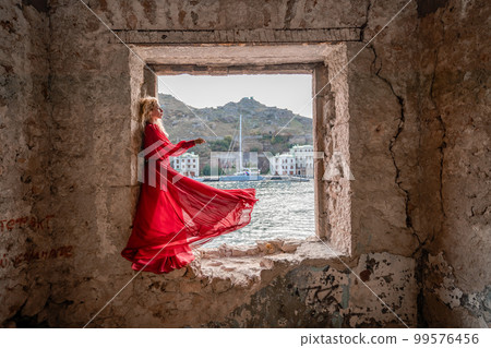 View of Balaklava Bay through an arched balcony in oriental style. The girl in a long red dress stands with her back. Abandoned mansion on the Black Sea coast View of Balaklava Bay through an arched balcony in oriental style. The girl in a long red dress stands with her back. Abandoned mansion on the Black Sea coast 99576456