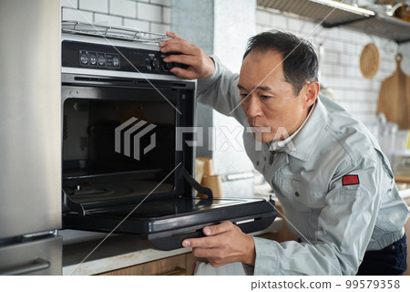 A repairman man inspecting the oven 99579358