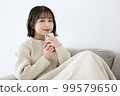 一個女人坐在沙發上，拿著智能手機微笑 99579650