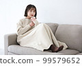 一個女人坐在沙發上，拿著智能手機微笑 99579652