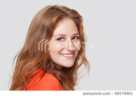 Happy cheerful young woman with red hair. Lady looking at camera with joyful and charming smile.  99579962
