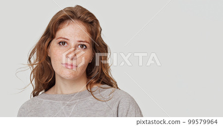 Portrait of a pretty young serious redhead woman posing isolated over white wall background 99579964
