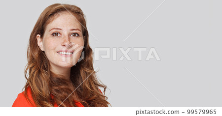 Portrait of young tender redhead woman with healthy freckled skin looking at camera  99579965