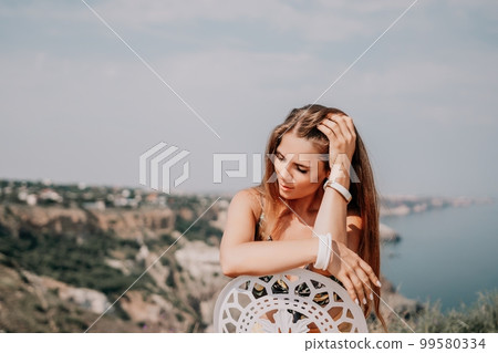 Happy boho woman portrait. Boho chic fashion style. Outdoor photo of free happy woman with long hair, sunny weather outdoors with sea mountains nature beautiful background. Happy boho woman portrait. Boho chic fashion style. Outdoor photo of free happy woman with long hair, sunny weather outdoors with sea mountains nature beautiful background. 99580334