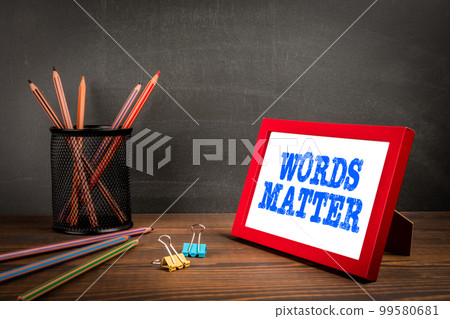 WORDS MATTER. Red picture frame with text on wood texture background 99580681