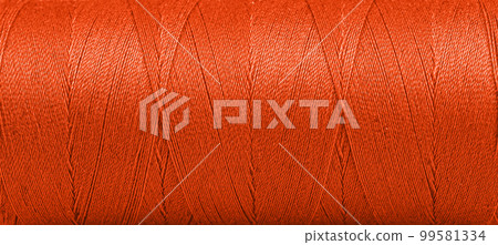 Texture of threads in a spool of Orange color on a white background 99581334