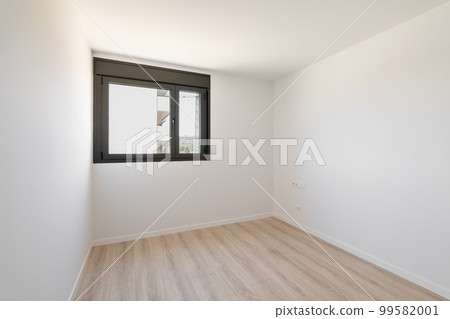 Small empty room without furniture. The floor is new light wood laminate. A window made of black plastic for airing the room. Daylight enters through the frosted glass in the window. Small empty room without furniture. The floor is new light wood laminate. A window made of black plastic for airing the room. Daylight enters through the frosted glass in the window. 99582001