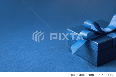 Part of Luxury gift box with a blue bow on dark blue. side view monochrome close up. Fathers day or Valentines day gift for him. Corporate gift concept or birthday party. Festive sale copy space 99582549