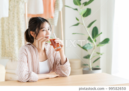 A young woman drinking vegetable juice 99582650