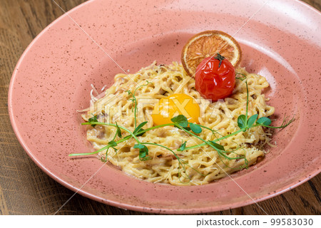 Carbonara sprinkled with greens and with a yolk in a plate 99583030