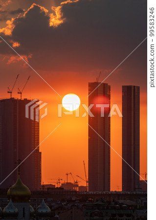 The setting sun over the skyscrapers of the office center on a summer evening. Sunset. 99583246