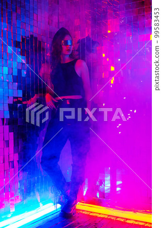 Portrait of a caucasian woman in sunglasses in neon light against a mirror wall. Portrait of a caucasian woman in sunglasses in neon light against a mirror wall. 99583453