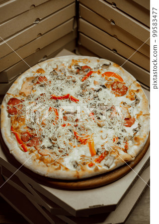 The boxes are on top of each other with one pizza between them 99583477