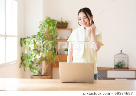 一個女人一邊鍛煉一邊拿著毛巾休息 一個女人一邊鍛煉一邊拿著毛巾休息 99584697