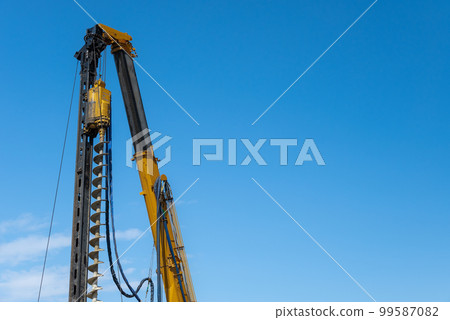 Blue sky and earth auger at a construction site 99587082