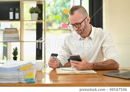 Millennial male hands holding credit cad and mobile phone, entering data for website form. Online shopping, e-commerce concept 99587506