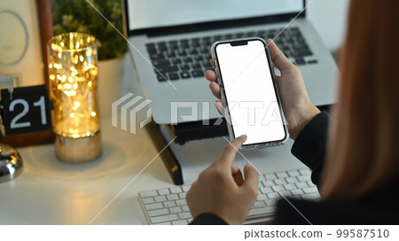 Closeup shot of woman hands holding smartphone and pointing with finger. Blank screen for your webpage or advertise text 99587510