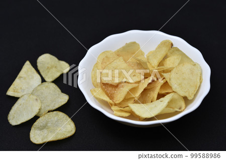 Potato chips in a white plate. Delicious pieces of chips. Salty fast food. 99588986