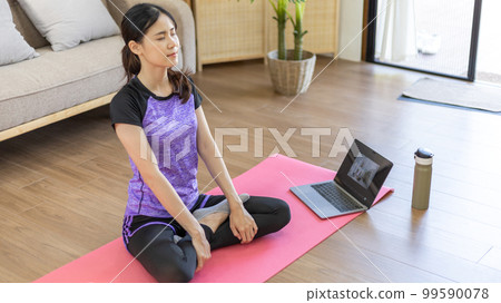 Woman looking at yoga teacher on laptop and doing light exercise in the living room at home, Watch live teaching or VDO on laptop, Dumbbells and a protein shake or bottle of water, Healthy exercise. Woman looking at yoga teacher on laptop and doing light exercise in the living room at home, Watch live teaching or VDO on laptop, Dumbbells and a protein shake or bottle of water, Healthy exercise. 99590078
