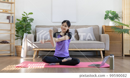 Woman looking at yoga teacher on laptop and doing light exercise in the living room at home, Watch live teaching or VDO on laptop, Dumbbells and a protein shake or bottle of water, Healthy exercise. Woman looking at yoga teacher on laptop and doing light exercise in the living room at home, Watch live teaching or VDO on laptop, Dumbbells and a protein shake or bottle of water, Healthy exercise. 99590082