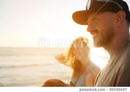 Close up of a smiling handsome young beard man and attractive woman with curly hair walking at the beach on sunset. couple in love in travel holiday vacation and having honeymoon after wedding. Close up of a smiling handsome young beard man and attractive woman with curly hair walking at the beach on sunset. couple in love in travel holiday vacation and having honeymoon after wedding. 99590497