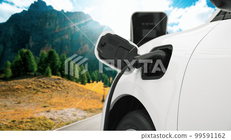 Progressive travel concept by EV car in remote mountain with charging station. 99591162