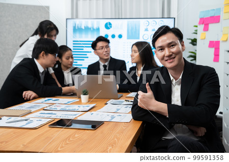 Focus portrait male manager in harmony office with businesspeople in background. Focus portrait male manager in harmony office with businesspeople in background. 99591358