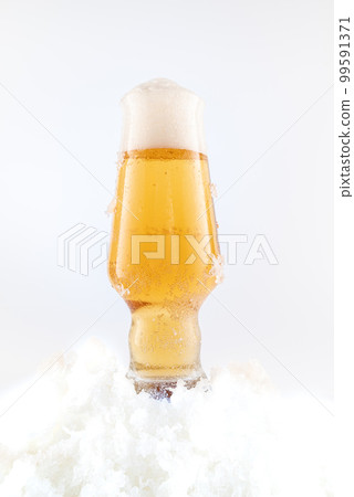 A glass of light beer on a white background. A glass of beer in the snow. Cool beer with foam. A glass of light beer on a white background. A glass of beer in the snow. Cool beer with foam. 99591371