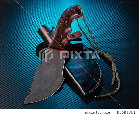 Bushcraft knife. Knife with saw and leather sheath. Blue illumination in the background. Survival knife. 99591391