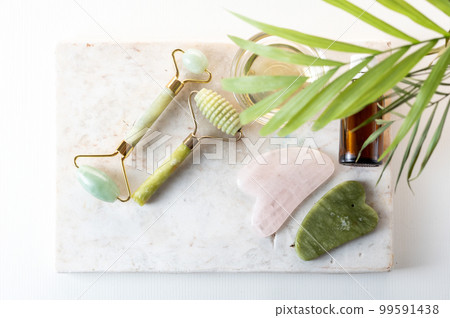 Cosmetic items and oil on a marble board. Cosmetics on the background of a palm leaf. Cosmetic items and oil on a marble board. Cosmetics on the background of a palm leaf. 99591438