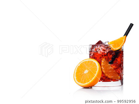 Negroni Cocktail in crystal glass with ice cubes and orange slices with straw and half Negroni Cocktail in crystal glass with ice cubes and orange slices with straw and half 99592956