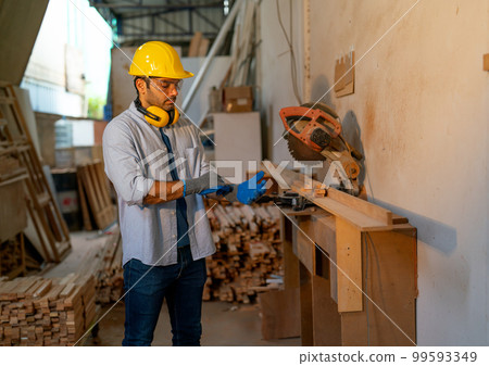 Wood worker or carpenter man wear glove before work with electrical saw in factory workplace Wood worker or carpenter man wear glove before work with electrical saw in factory workplace 99593349