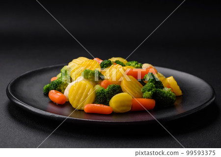 Delicious fresh vegetables steamed carrots, broccoli, cauliflower on a black plate Delicious fresh vegetables steamed carrots, broccoli, cauliflower on a black plate 99593375