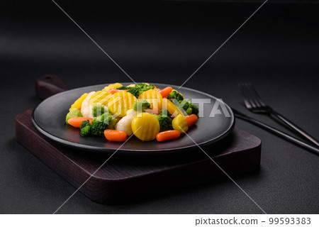 Delicious fresh vegetables steamed carrots, broccoli, cauliflower on a black plate 99593383