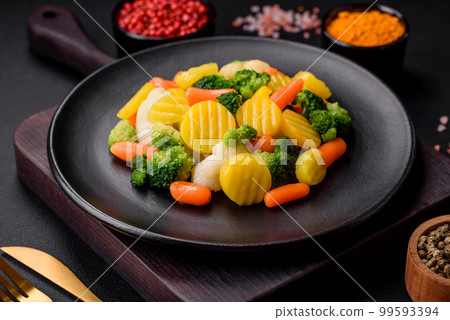 Delicious fresh vegetables steamed carrots, broccoli, cauliflower on a black plate 99593394