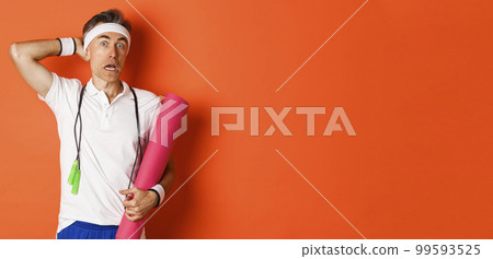 Concept of workout, gym and lifestyle. Image of awkward middle-aged athlete, looking confused, holding yoga mat and skipping rope, standing over orange background 99593525