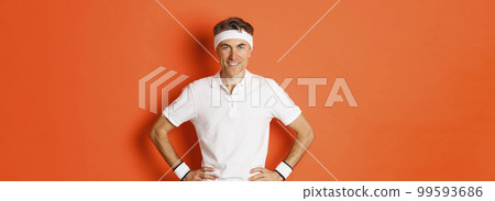 Portrait of confident middle-aged male athlete, wearing sportswear, doing exercises and smiling, workout over orange background 99593686
